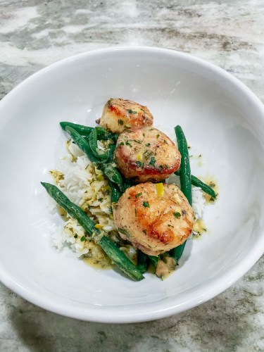 Bowl with rice, green beans, and scallops with a herb sauce on top