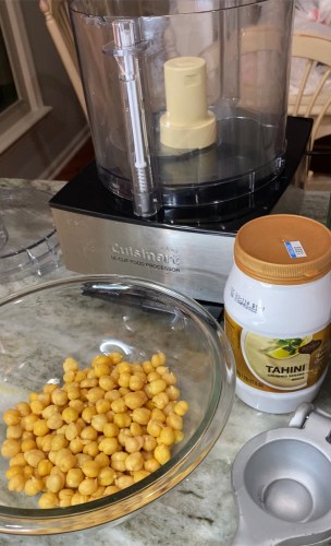 food processor, bowl of chickpeas, and jar of tahini